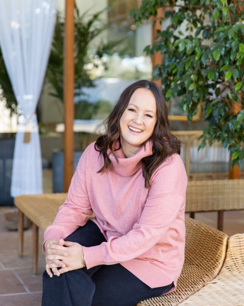 Kelley Stevens in pink sweater sitting in a wooden chair