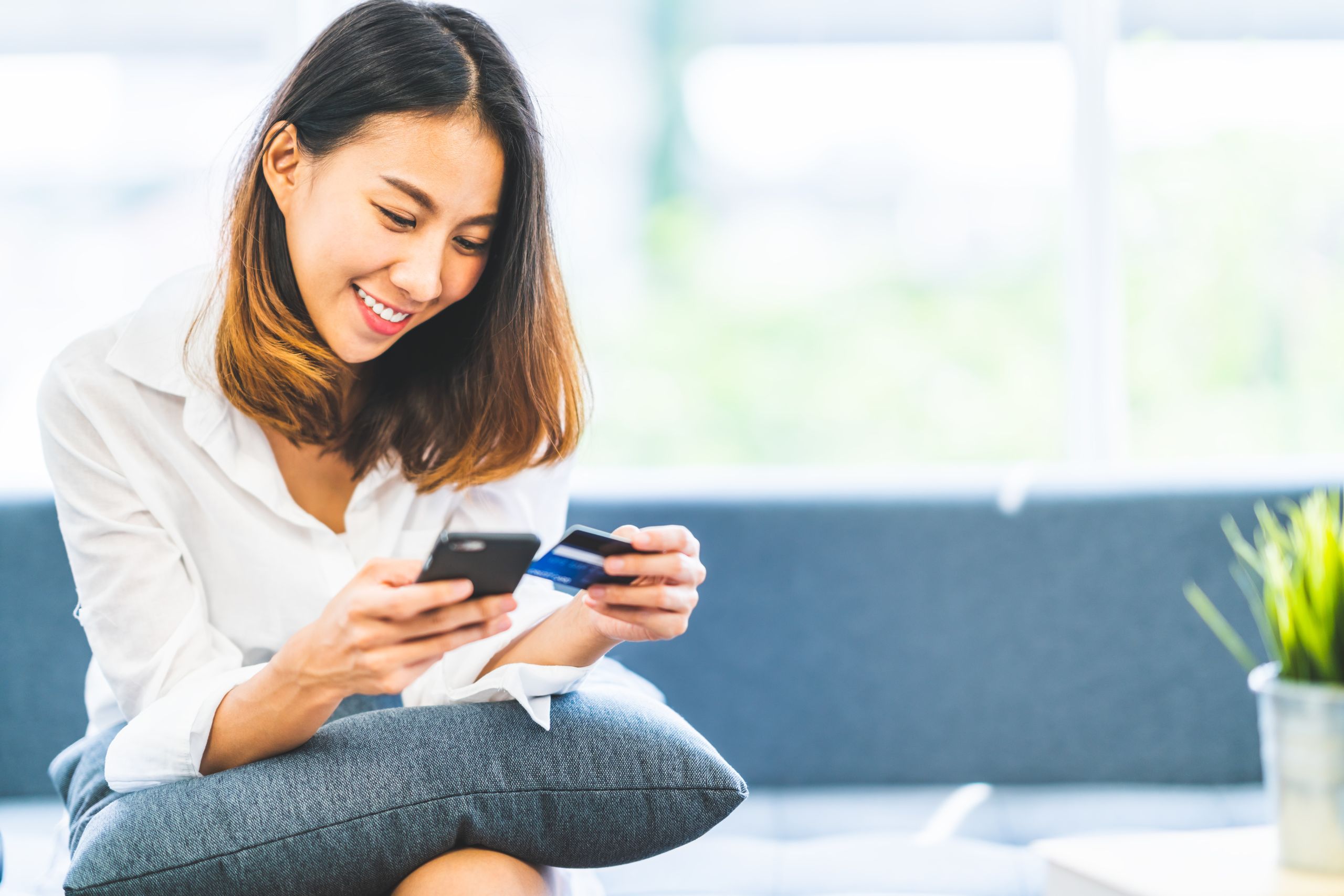 Woman looking at her phone and card to make a payment