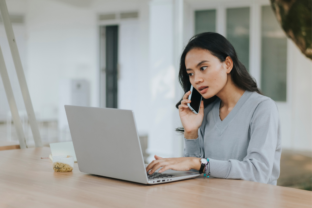 A woman on phone talking while typing on the laptop - The Private Practice Pro