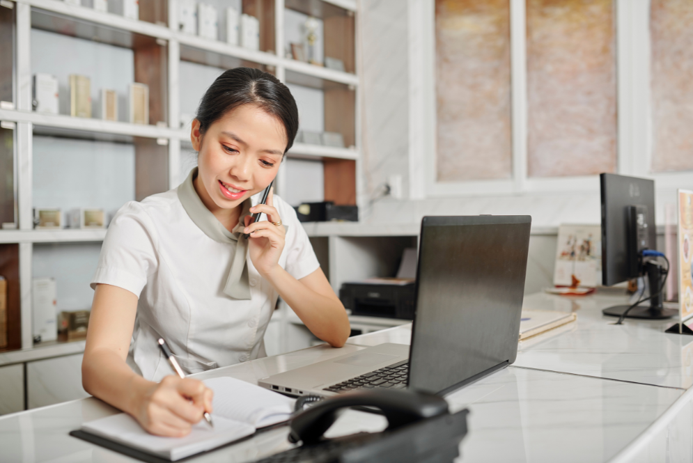 A woman on phone talking while writing down notes - The Private Practice Pro